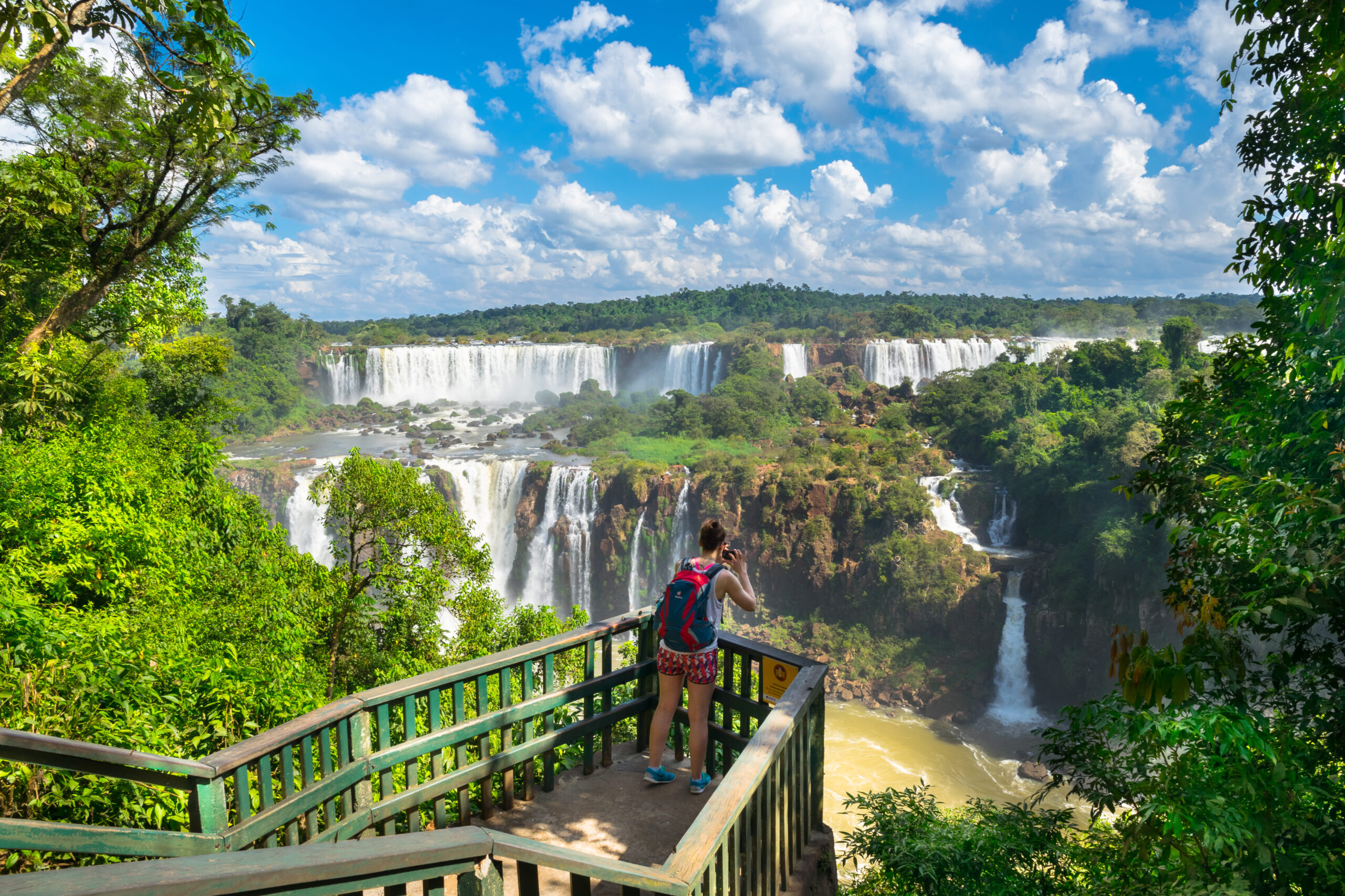 Voyageuse photographiant les chutes d'Iguazu depuis un belvédère de la passerelle, entourée de forêt