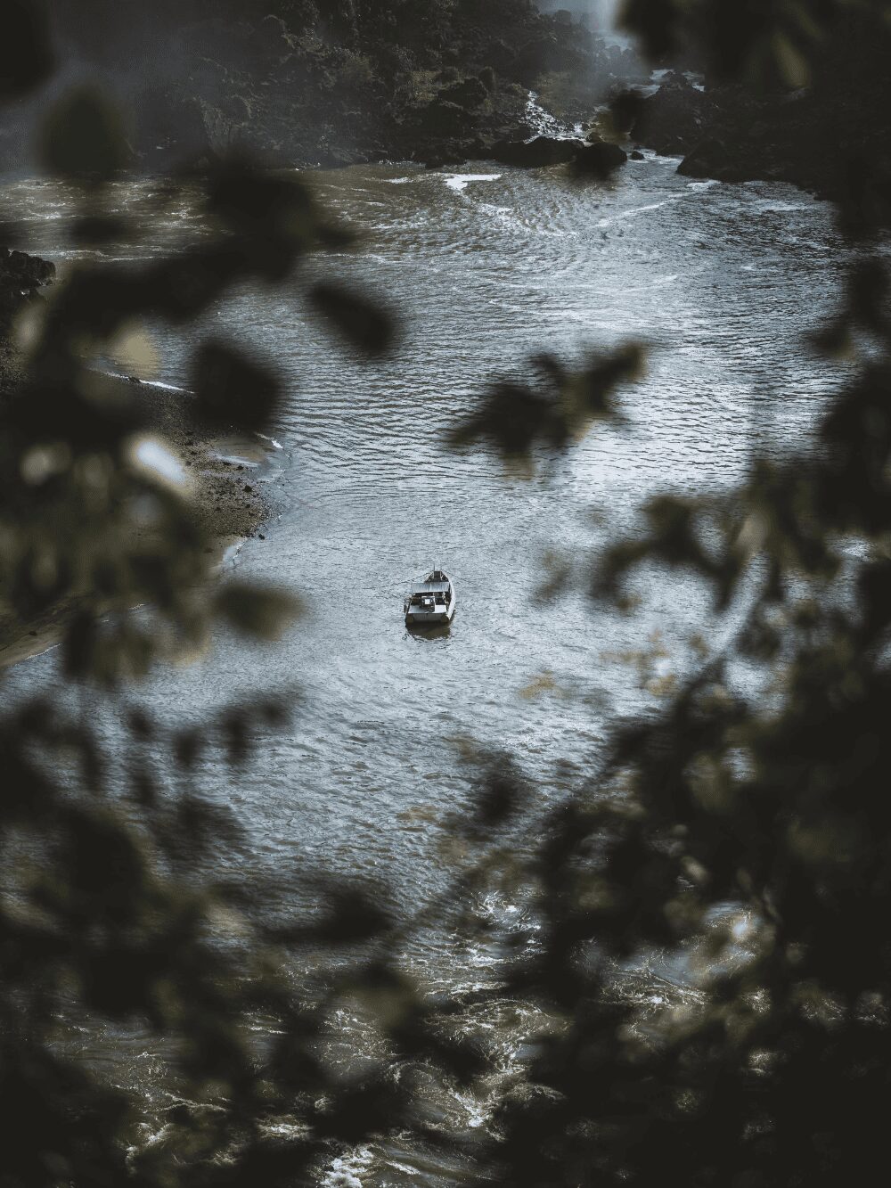Petit bateau sur le fleuve Iguazu vu d'en haut à travers le feuillage de la forêt