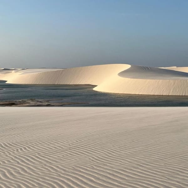 Dunes de sable blanc qui entourent une lagune en fin de journée aux Lençóis Maranhenses