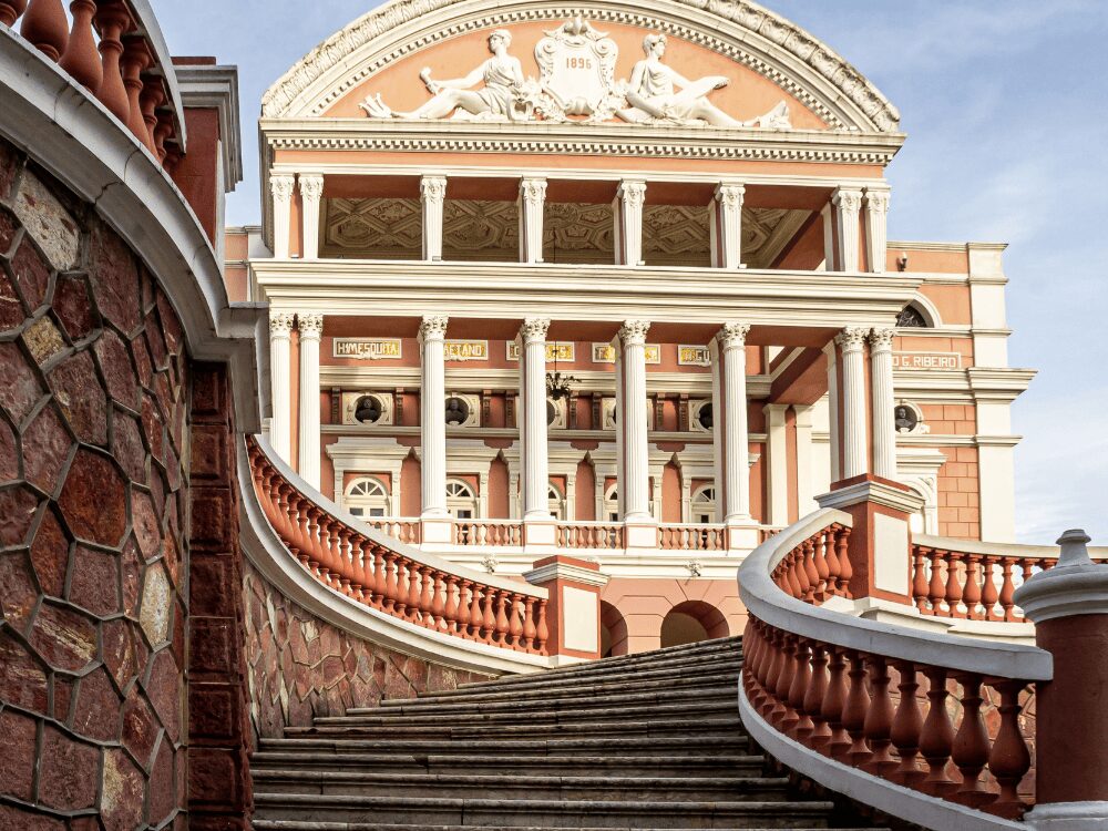 Escalier courbe menant à la façade rose et aux colonnes blanches du Teatro Amazonas, l’opéra de Manaus